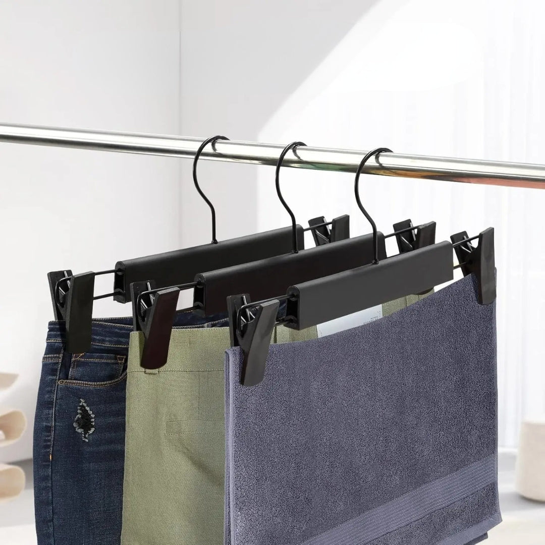 Dressing ouvert moderne avec cintres pince noirs suspendant des pantalons bien alignés sur une tringle élégante.