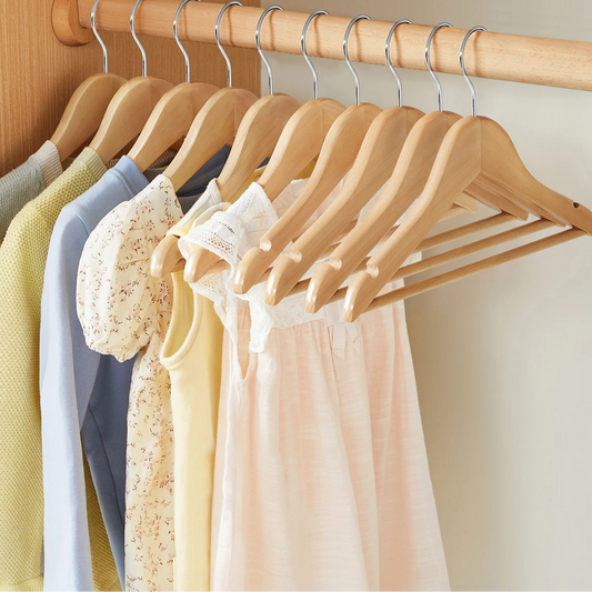 Cintre enfant en bois d’érable suspendant des vêtements de bébé