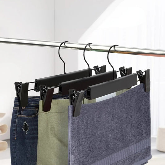 Dressing ouvert moderne avec cintres pince noirs suspendant des pantalons bien alignés sur une tringle élégante.