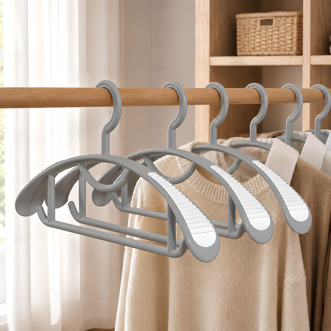 Cintres gris à épaules larges avec zones antidérapantes blanches portant des vêtements dans un dressing organisé