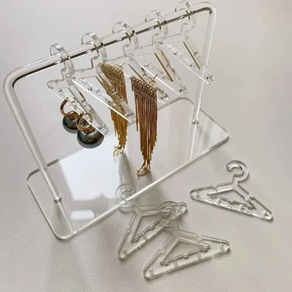 Rangement pour bijoux cristallin en acrylique transparent avec mini cintres, idéal pour organiser boucles d’oreilles et colliers avec élégance.